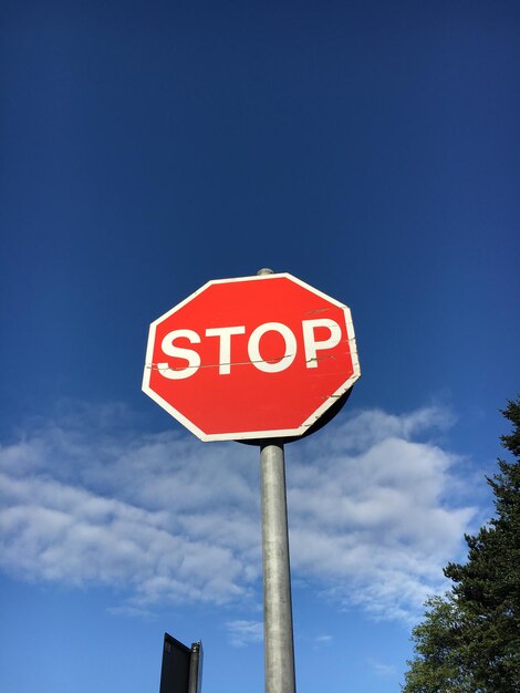 Low angle view of stop sign against blue sky