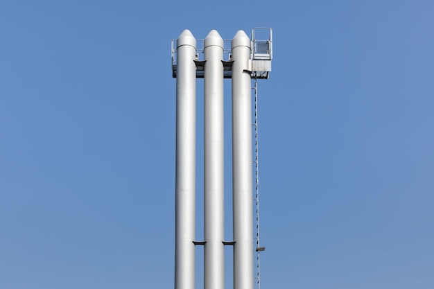 low angle view of storage tanks against clear blue sky
