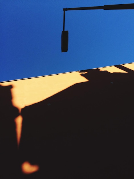 Foto vista a basso angolo della luce stradale e dell'edificio contro un cielo blu limpido