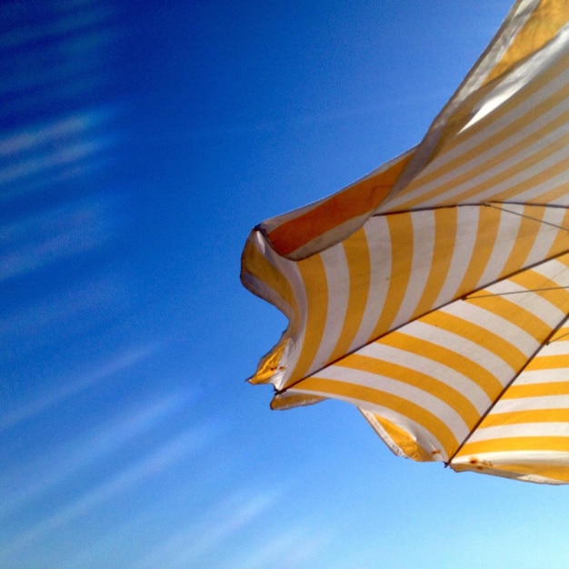 Foto vista a bassa angolazione di un ombrello a righe contro un cielo blu limpido