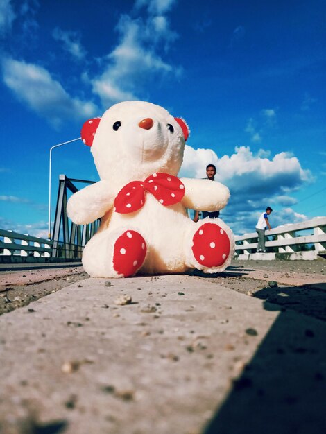 Low angle view of stuffed toy on land against blue sky