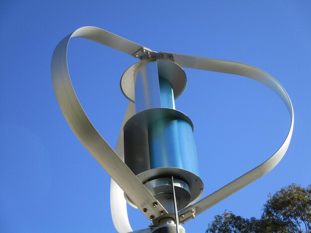 Low angle view of suburban metal wind turbine against blue sky