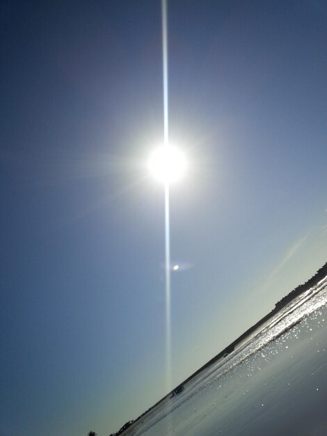 Low angle view of sun shining through clouds