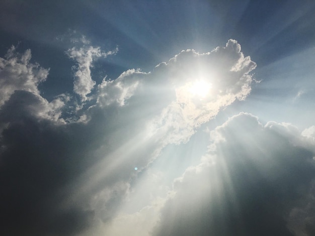 low angle view of sunbeams streaming from clouds