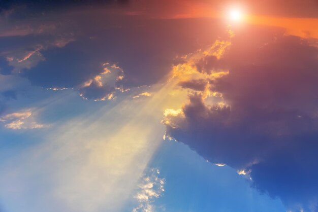 Low angle view of sunlight streaming through clouds during sunset