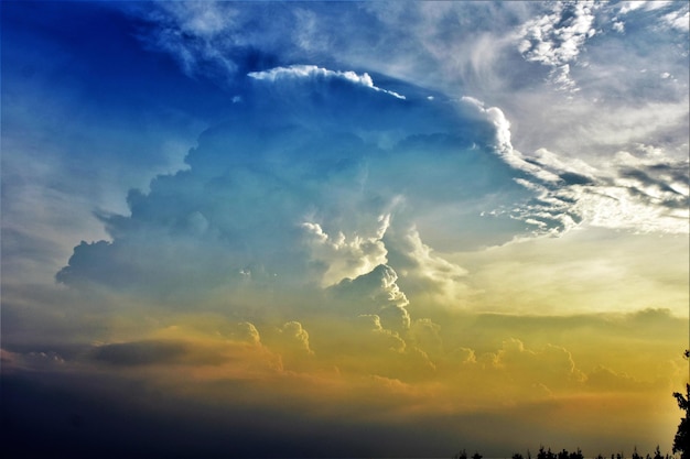 Low angle view of sunlight streaming through clouds during sunset