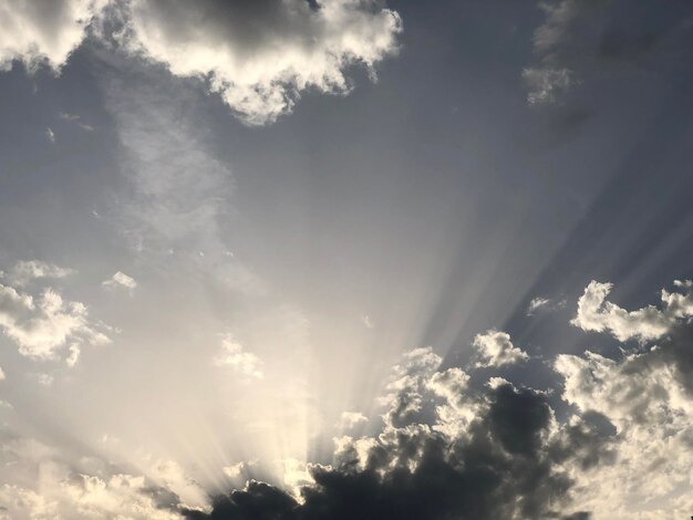 Low angle view of sunlight streaming through clouds