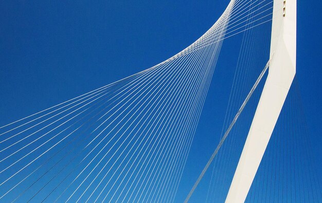 Low angle view of suspension bridge against blue sky