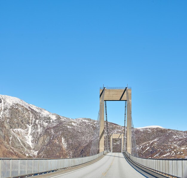 Low angle view of suspension bridge against clear blue sky