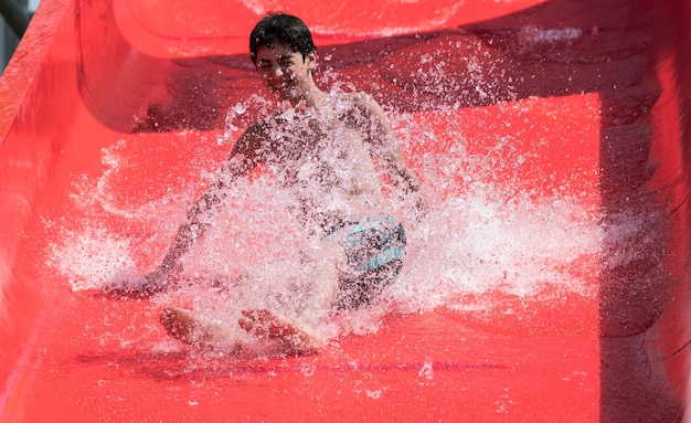 Photo low angle view of teenage boy sliding on red water slide