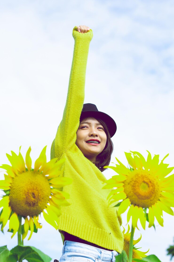 Photo 天空の向こうに日<unk>が立っている手を挙げた十代の女の子の低角度の写真