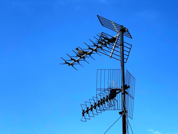 Low angle view of telephone pole against clear blue sky