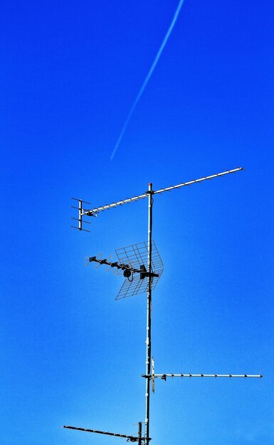 Low angle view of telephone pole against clear blue sky