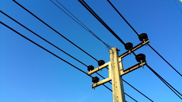 Low angle view of telephone pole against clear blue sky