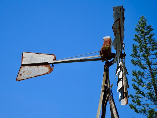 Low angle view of telephone pole against clear blue sky