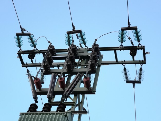 Low angle view of telephone pole against clear blue sky