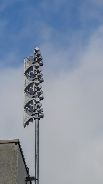 Low angle view of telephone pole by building against sky