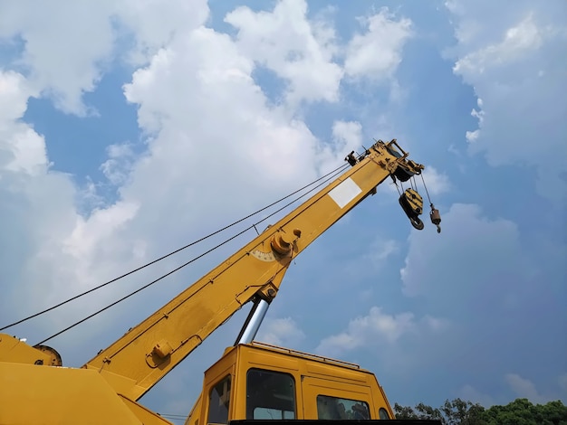 Low Angle View of Telescopic Boom with Hoist of Yellow Crane at Construction Site Against Cloudy Sky