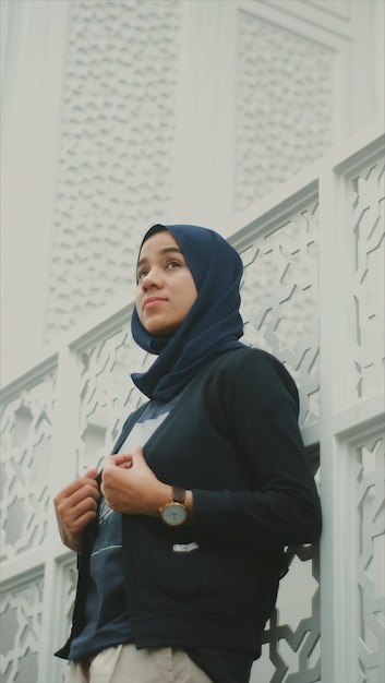 Photo low angle view of thoughtful young woman wearing hijab by retaining wall