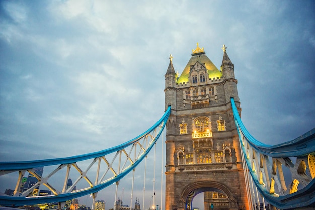 low angle view of tower bridge against cloudy sky in city at dusk