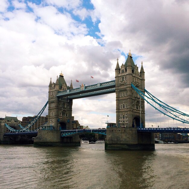 Low angle view of tower bridge against cloudy sky