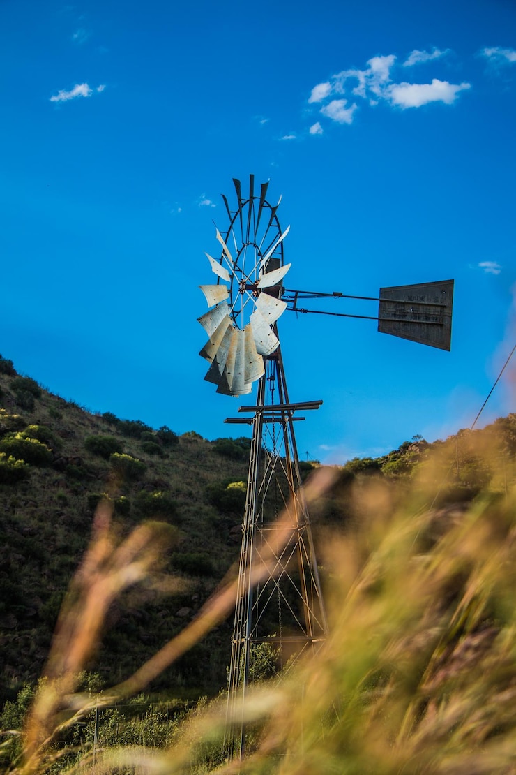 फोटो low angle view of traditional windmill on field against blue sky