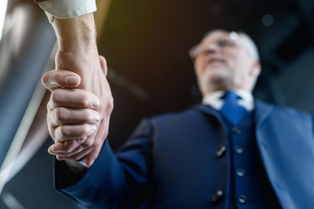 Foto inquadratura dal basso di due uomini d'affari che si stringono la mano mentre sono in piedi all'interno