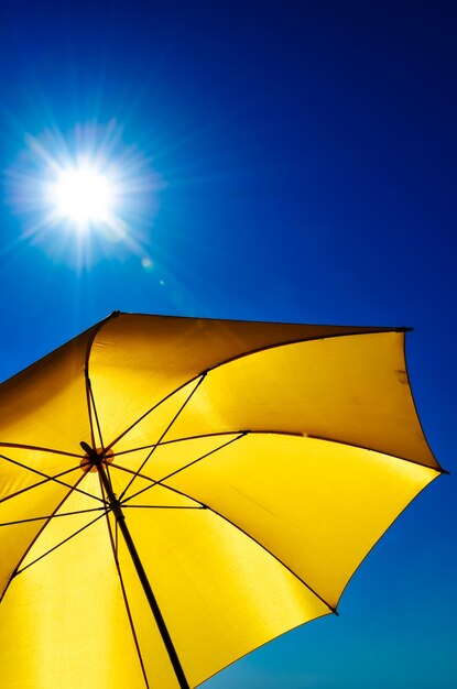 Low angle view of umbrella against clear blue sky