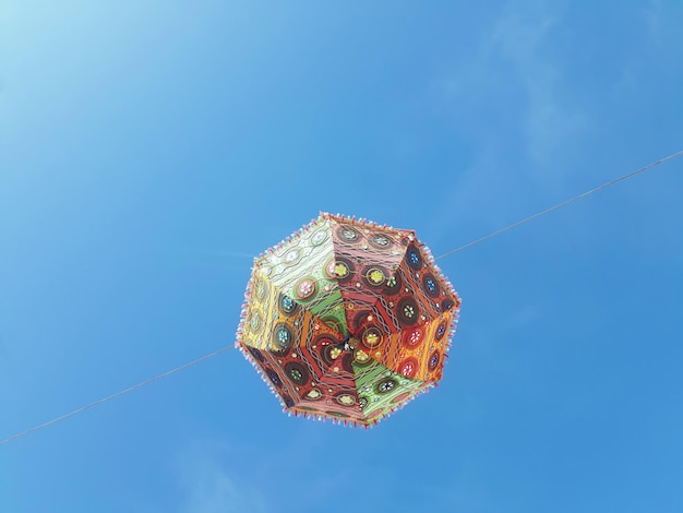 Low angle view of umbrella hanging against clear blue sky