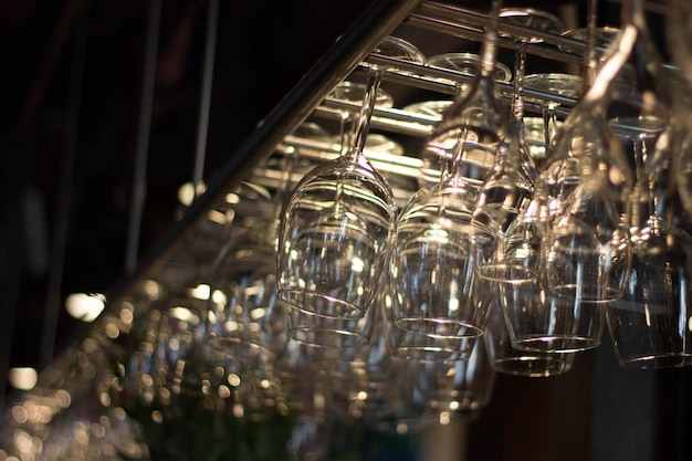 low angle view of upside down wineglasses hanging on rack at bar