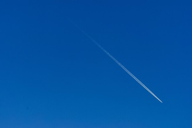 Low angle view of vapor trail against clear blue sky