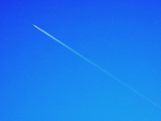 Low angle view of vapor trail against clear blue sky