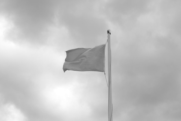 Photo low angle view of waving flag against cloudy sky