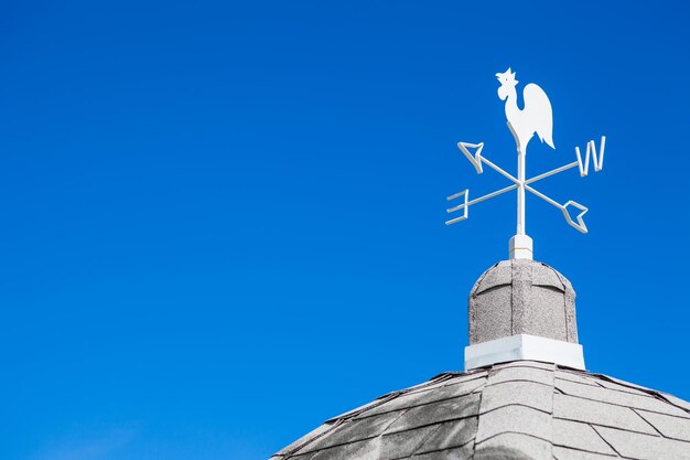 Low angle view of weather vane against blue sky