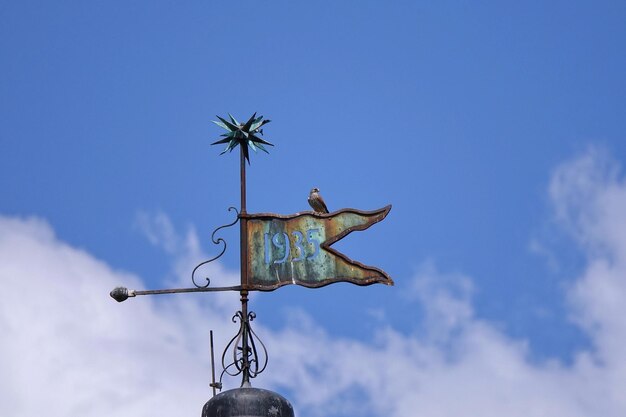 Photo low angle view of weather vane against blue sky