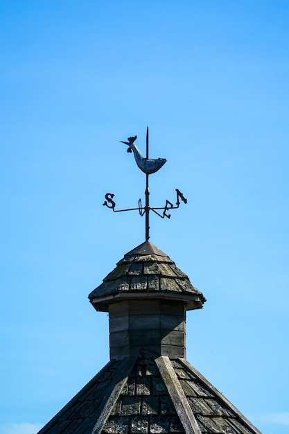 Low angle view of weather vane against blue sky