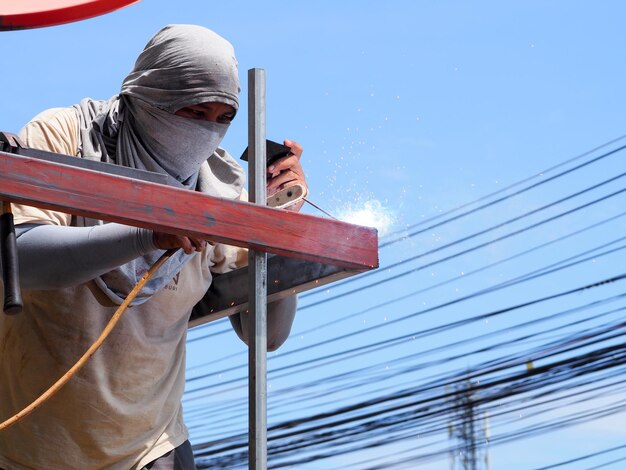 Photo low angle view of welder working against clear sky