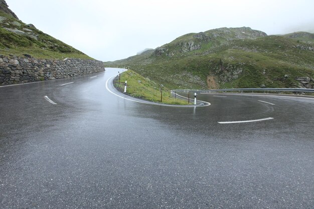 Low angle view of wet road at mountain against clear sky