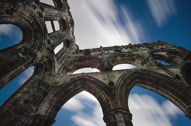 Low angle view of whitby abbey against blue sky