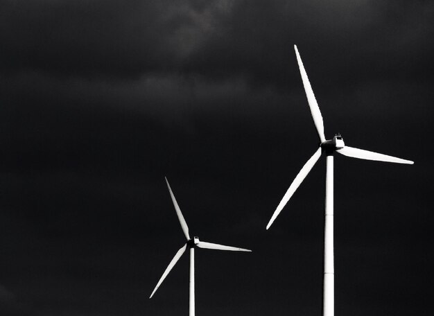 Photo low angle view of wind turbines against cloudy sky