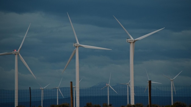 Low angle view of windmills against cloudy sky