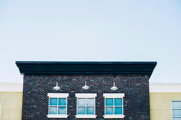 Low angle view of windows on brick wall building against clear sky