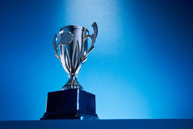 Low angle view of winning trophy against blue background