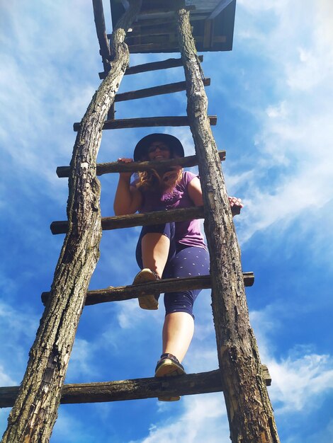 Photo low angle view of woman against trees against sky