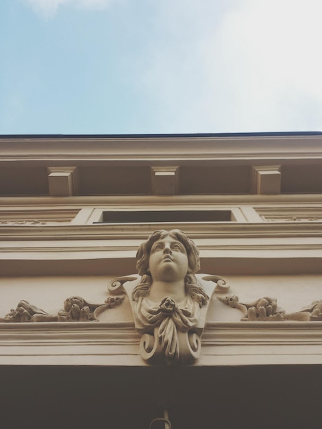 Foto vista a bassa angolazione della testa di una donna scolpita sull'edificio contro un cielo limpido