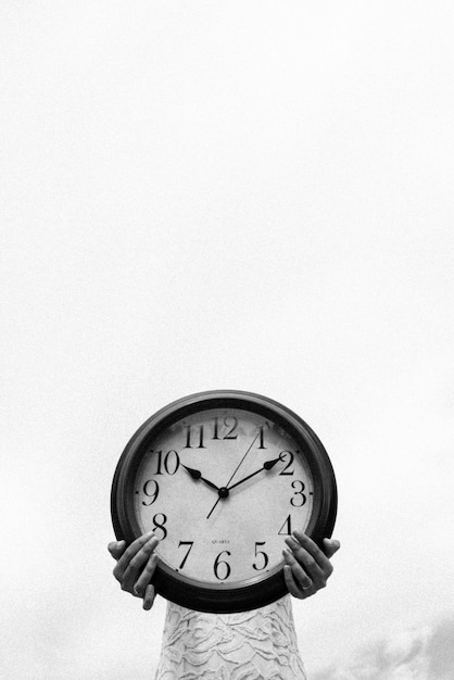 Low angle view of woman holding clock against clear sky