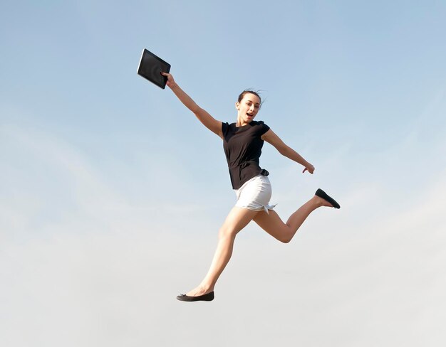 Low angle view of woman jumping against sky