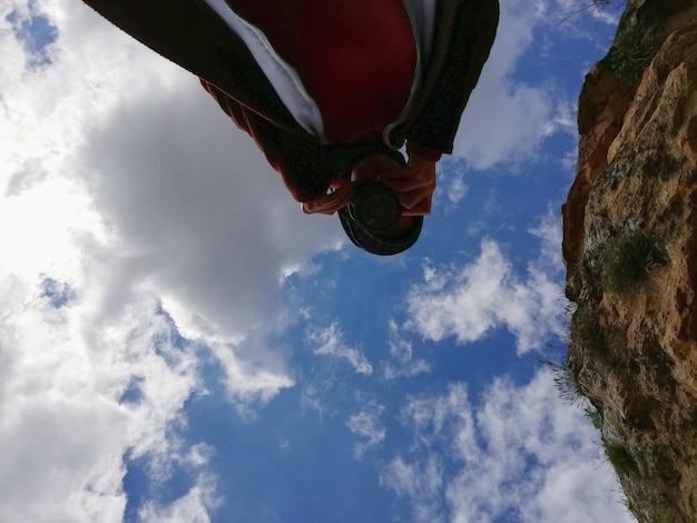Foto vista a bassa angolazione di una donna che fotografa contro il cielo