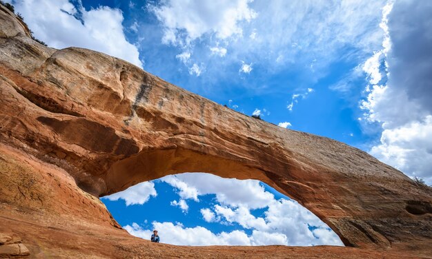 Low angle view of woman on rock formation against sky