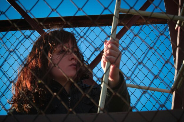 Photo low angle view of woman seen through chainlink fence